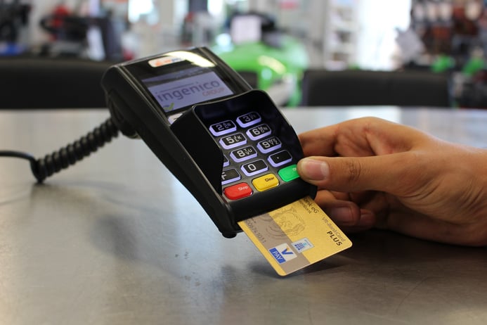 A credit card with a chip inserted into an Ingenico PIN pad