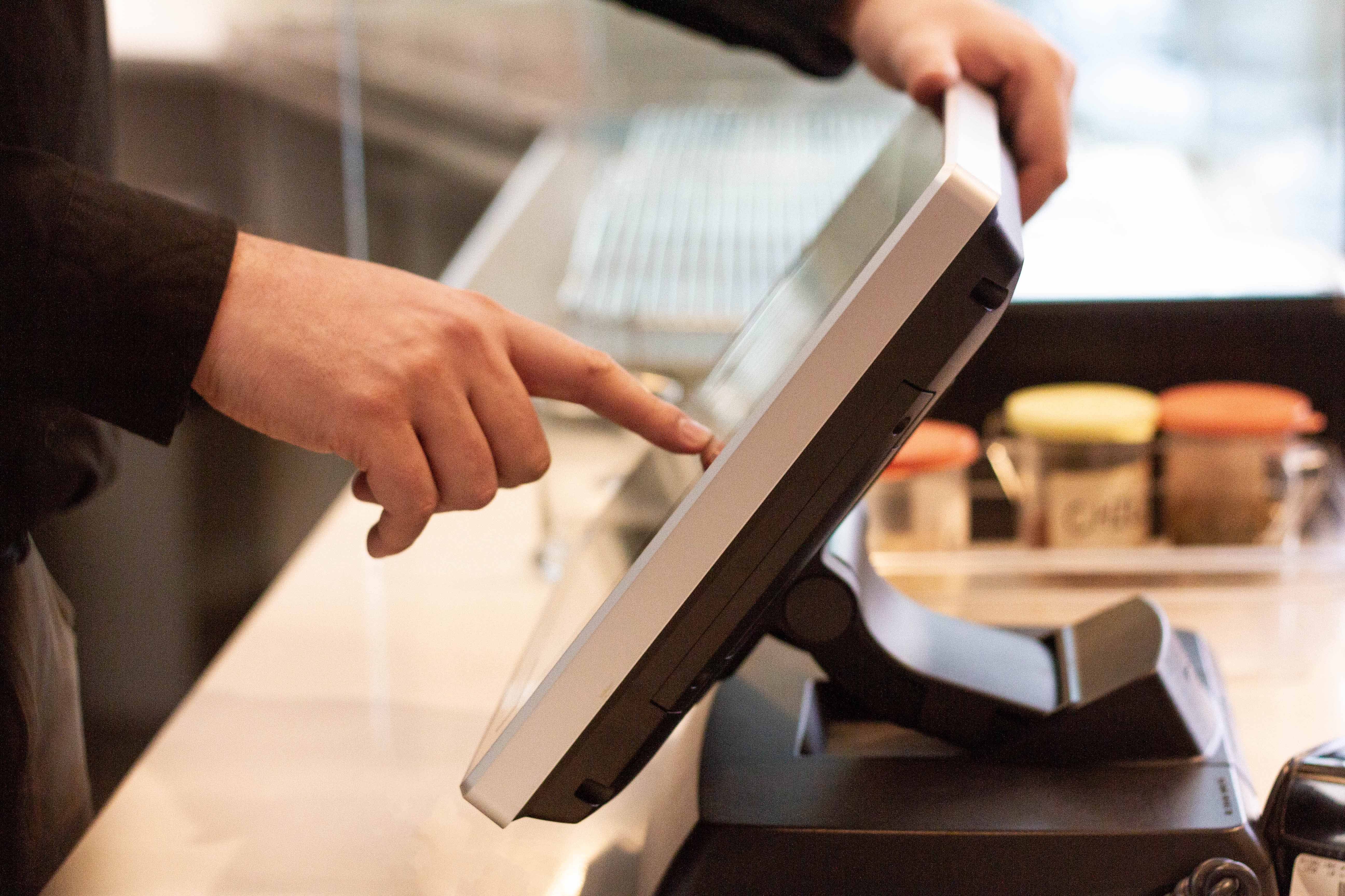 Pizzeria employee using a touchscreen POS display