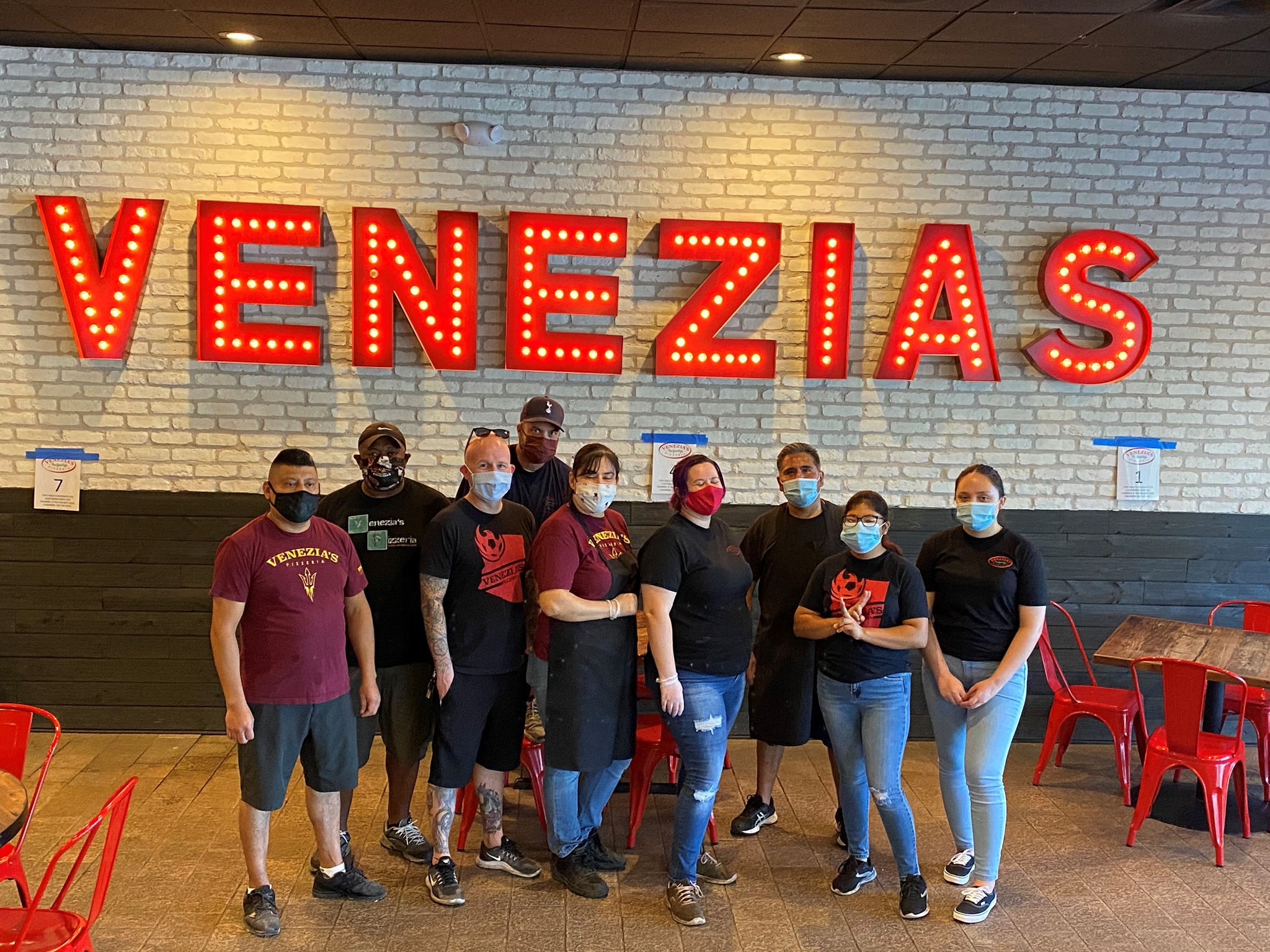 Venezia's Pizzeria staff standing in front of their sign