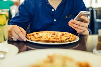 A person eating a pizza and looking at their phone