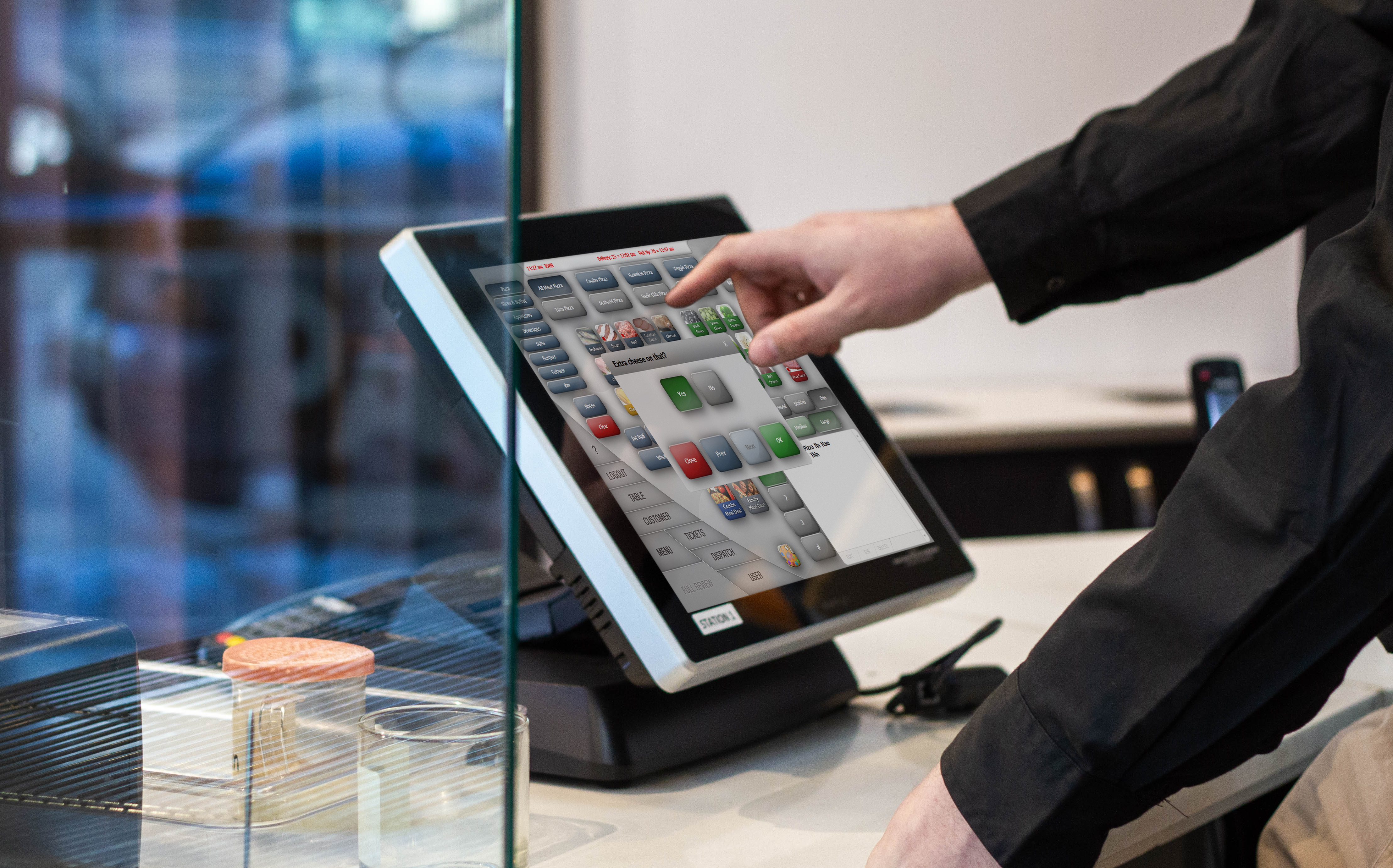 The order entry screen on a POS with a finger using the touch screen